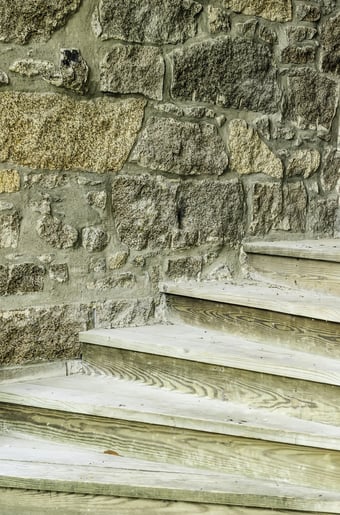Study in textural contrast Plain wooden steps against stone wall of campus building